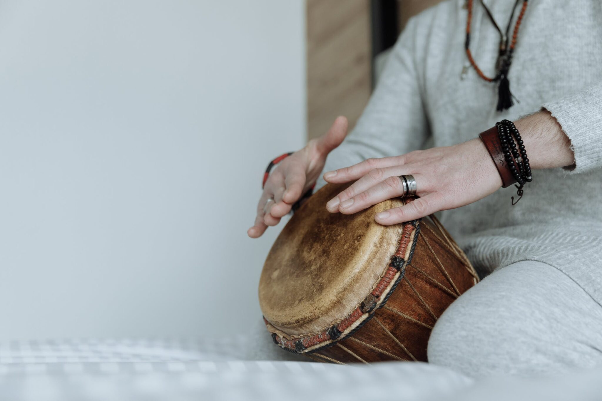 Hands practicing rhythm on a djembe at home