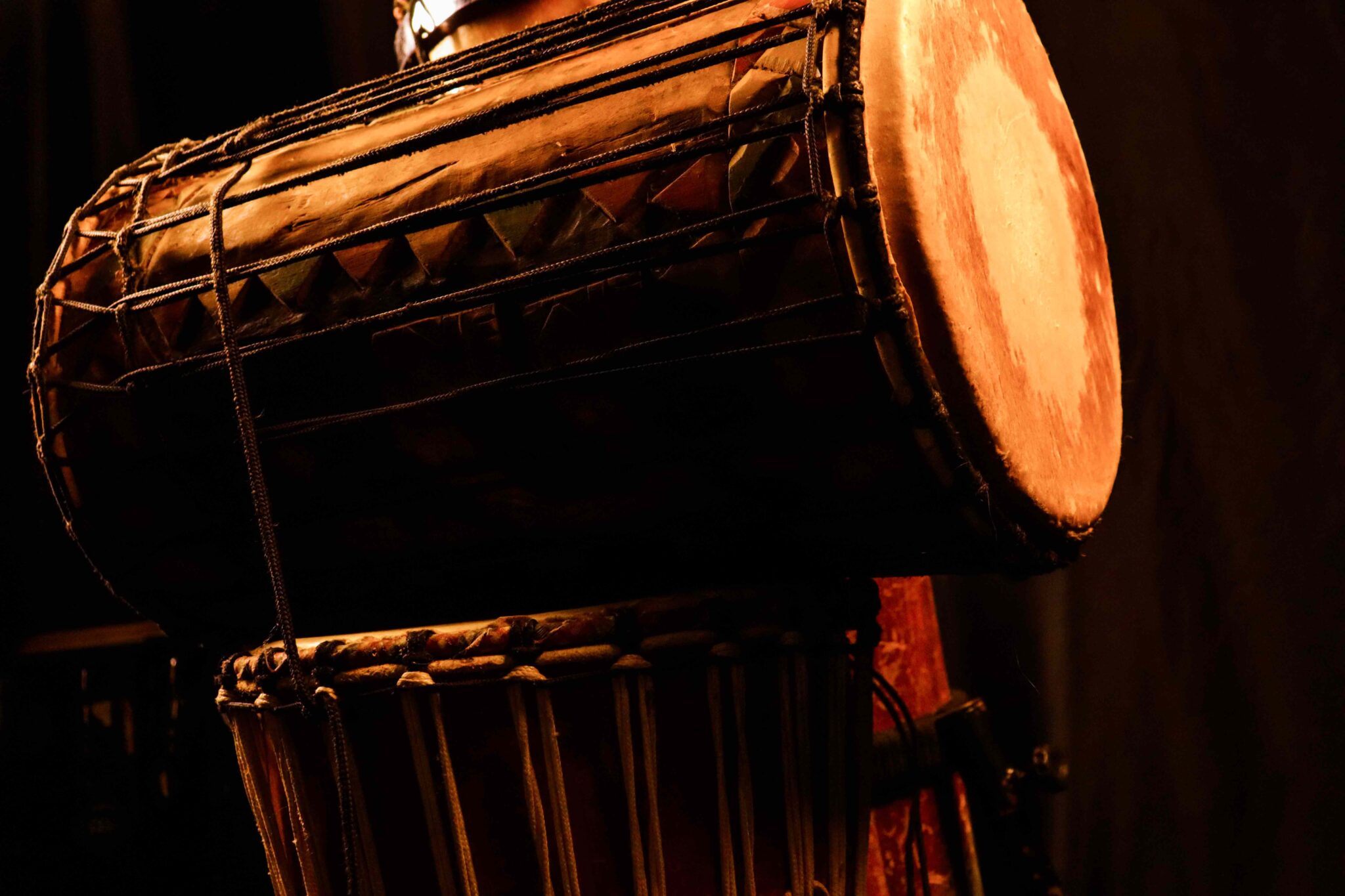 Hand-carved sangban and djembe drums in warm low light